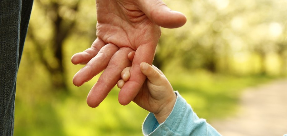 Elternteil hält Kinderhand